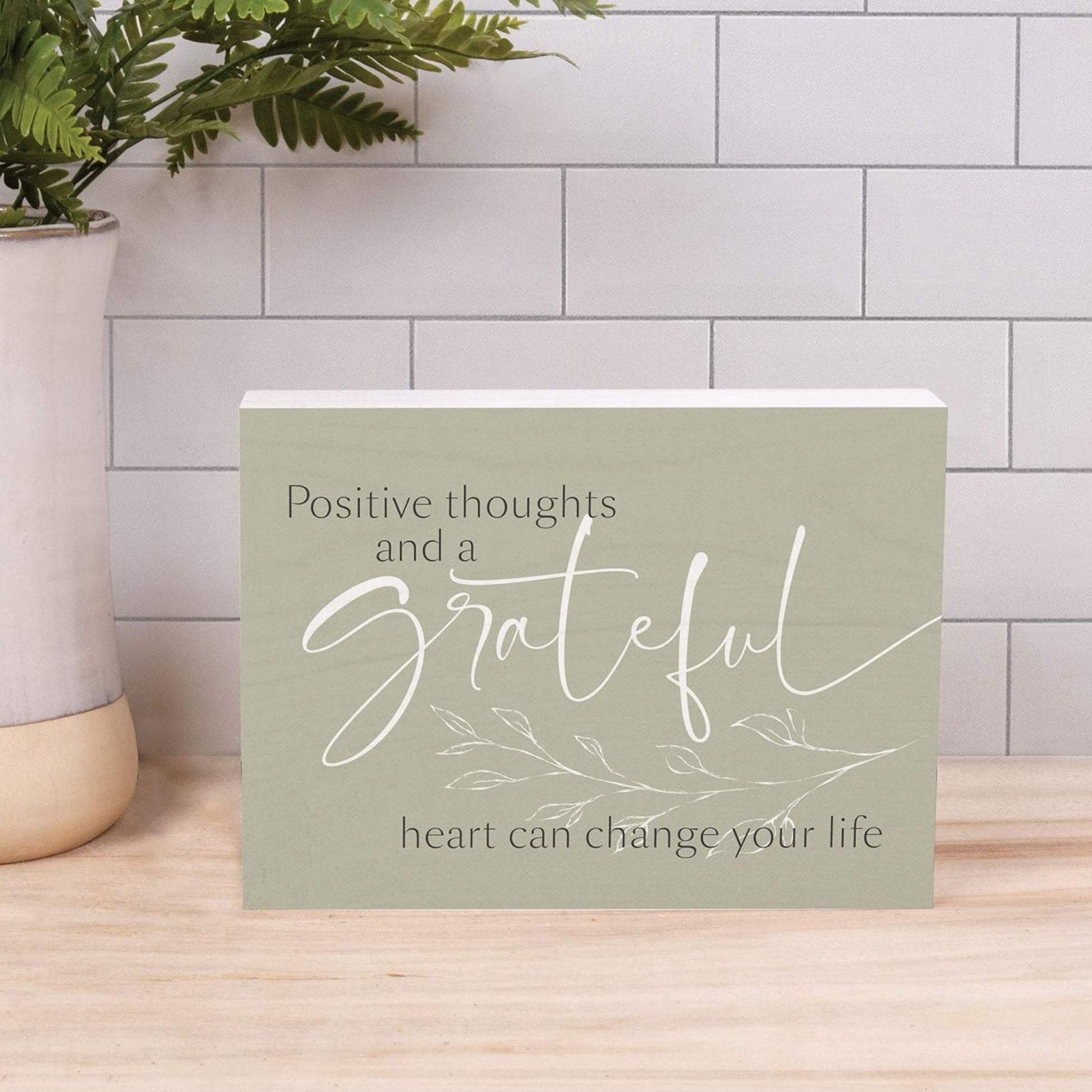 Inspirational Word Wood Block - Positive Thoughts and a Grateful Heart Can Change Your Life on Butcher Block Kitchen Counter in front of subway tile and next to greenery in vase | InsideOutCatalog.com