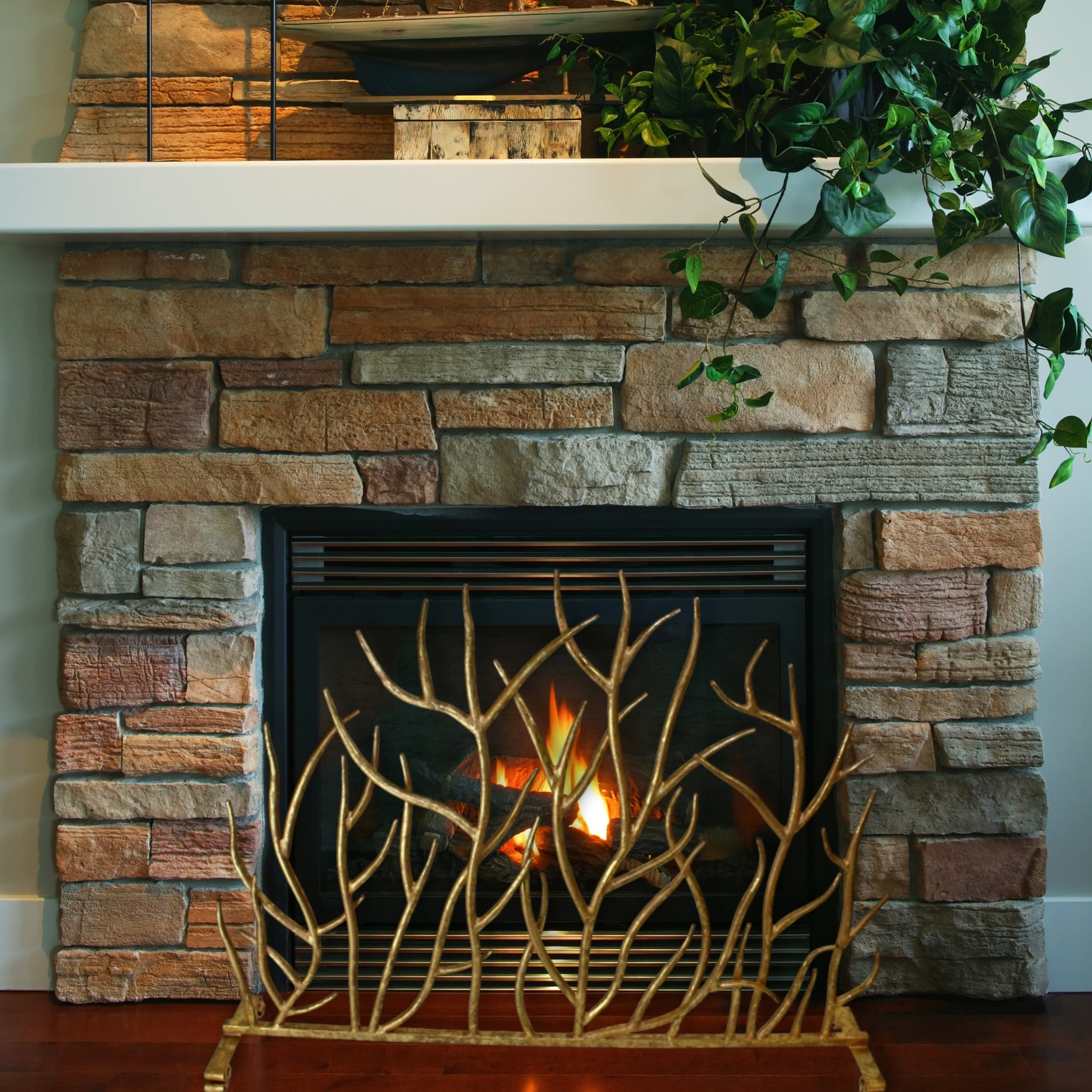 Italian Gold Iron Twig Decorative Fire Screen in front of stone fireplace with gas insert | InsideOutCatalog.com