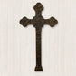 A large wall-mounted iron cross with intricate designs, finished in brown taupe, displayed against a textured background | INSIDE OUT - InsideOutCatalog.com