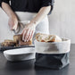 Reversible Linen Bread Pouch - Black and Grey | Woman slicing bread next to dough bowl and our linen bread bag filled with warm bread | INSIDE OUT | InsideOutCatalog.com